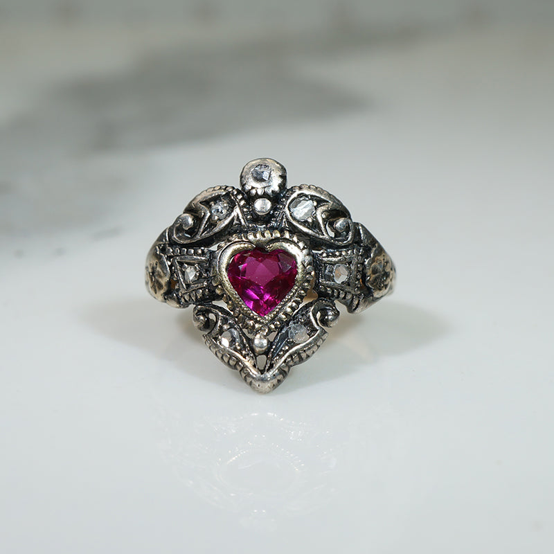 Silver ring with a heart-shaped pink gemstone and rose cut diamonds circa 1820 on a light background