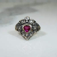 Silver ring with a heart-shaped pink gemstone and rose cut diamonds circa 1820 on a light background