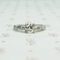fancy triple split prongs hold an old euro diamond in a platinum setting all original circa 1940 engagement ring with interesting shaped diamond set side details.