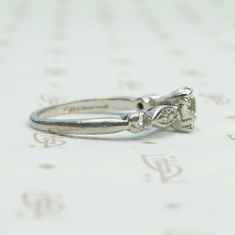 fancy triple split prongs hold an old euro diamond in a platinum setting all original circa 1940 engagement ring with interesting shaped diamond set side details.