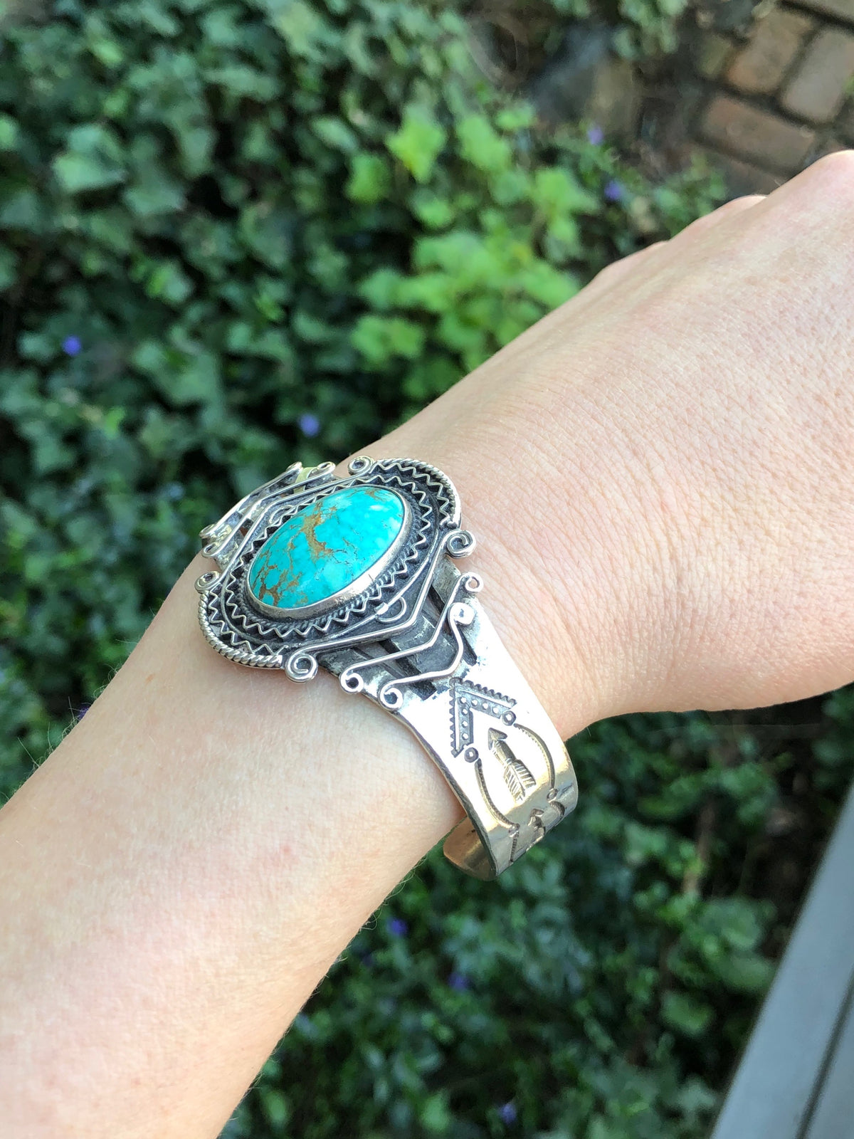 american silver cuff with arrow pattern and big turquoise on wrist