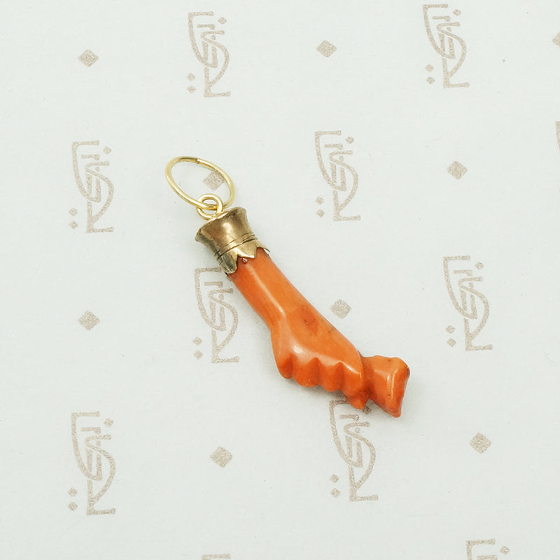 carved red coral hand holding a rose bud with a yellow gold cuff.