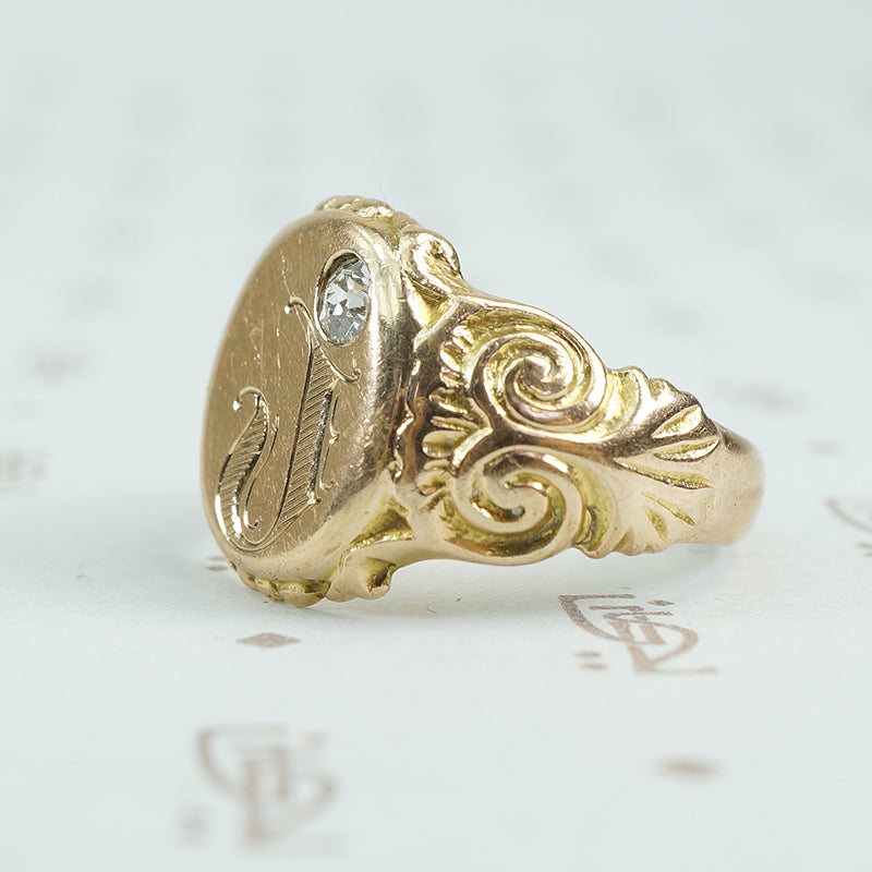 Gold signet ring with engraved j topped with a mine cut diamond side view