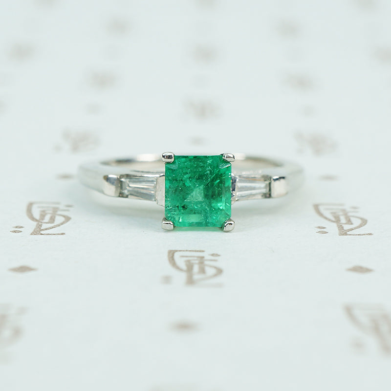 Square green emerald in platinum engaement ring with diamond baguette sides