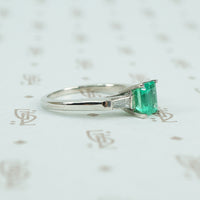 Square green emerald in platinum engaement ring with diamond baguette sides