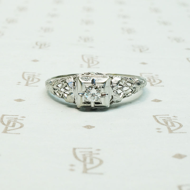 lacy filigree white gold diamond ring with a square set diamond