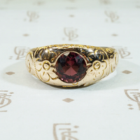 flowers and flourishes cover the surface of this 12k gold gypsy band set with a pretty garnet