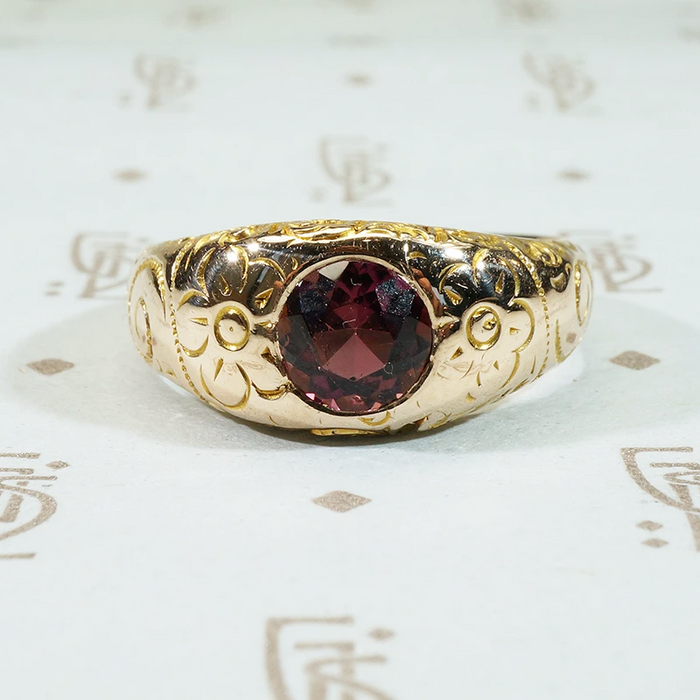 flowers and flourishes cover the surface of this 12k gold gypsy band set with a pretty garnet