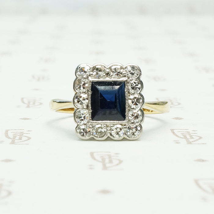 an emerald cut .60ct inky blue sapphire framed by diamonds in 18k yellow gold and platinum