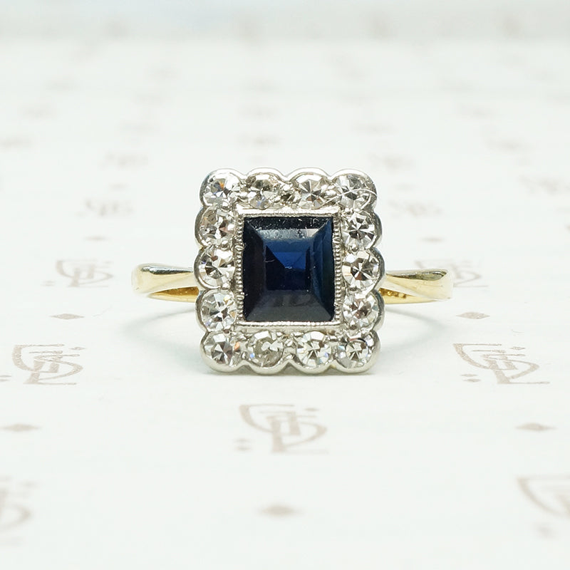 an emerald cut .60ct inky blue sapphire framed by diamonds in 18k yellow gold and platinum