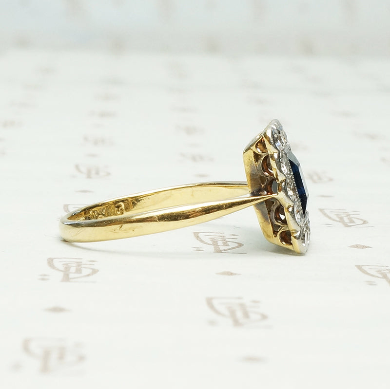 an emerald cut .60ct inky blue sapphire framed by diamonds in 18k yellow gold and platinum