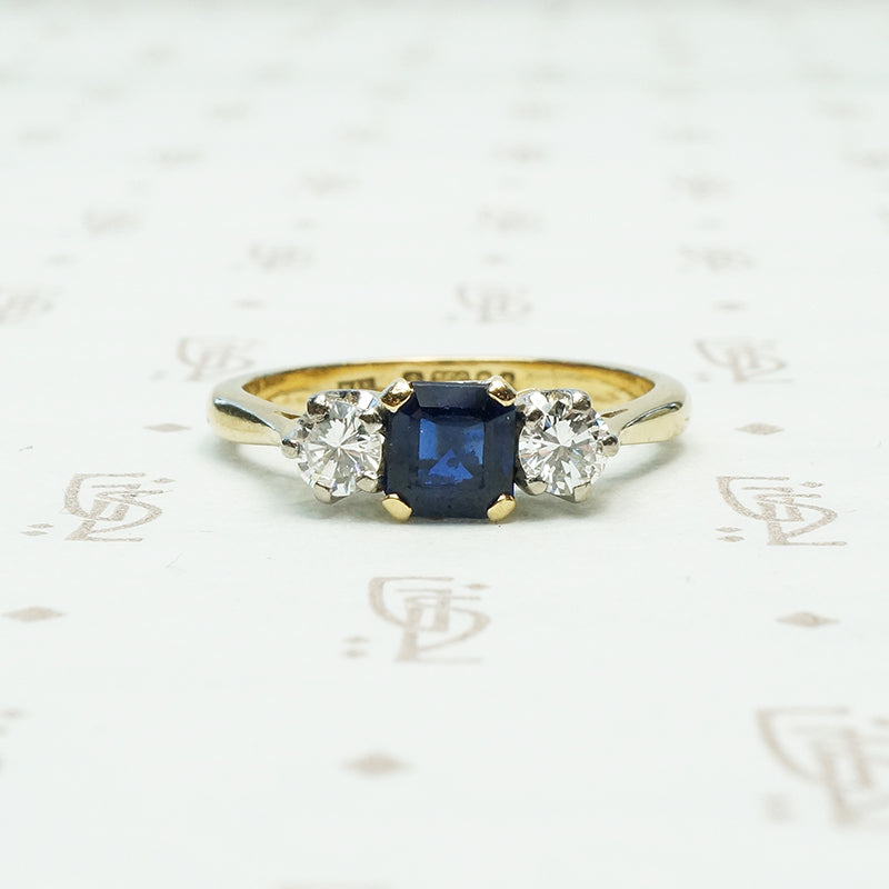 square sapphire set between 2 round white natural diamonds 18k yellow gold and platinum 3 stone ring