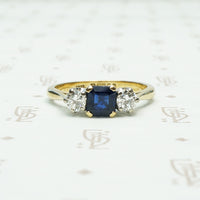 square sapphire set between 2 round white natural diamonds 18k yellow gold and platinum 3 stone ring