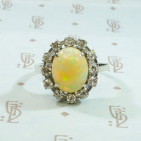 bright and firey oval opal surrounded by diamonds in 14k white gold ring