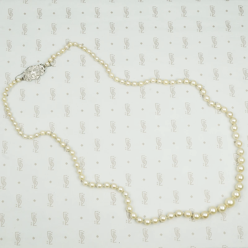 Lovelu long graduated strand of matinee length cultured graduated pearls with an elaborate diamond and platinum clasp