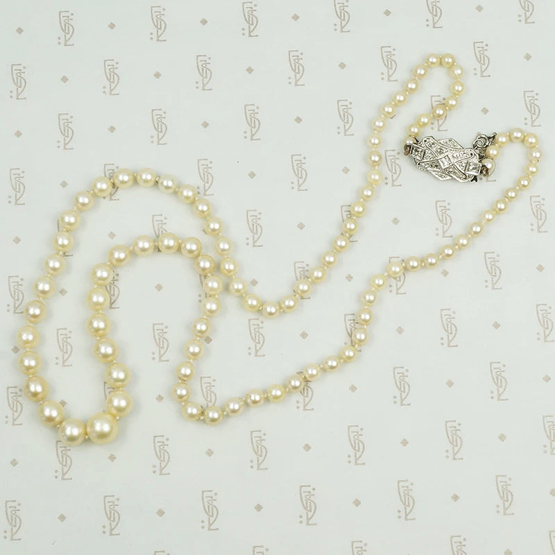 Lovelu long graduated strand of matinee length cultured graduated pearls with an elaborate diamond and platinum clasp