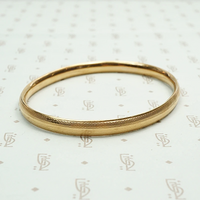 Engraved Gold Vintage Bangle Signed Krementz. Angled view.