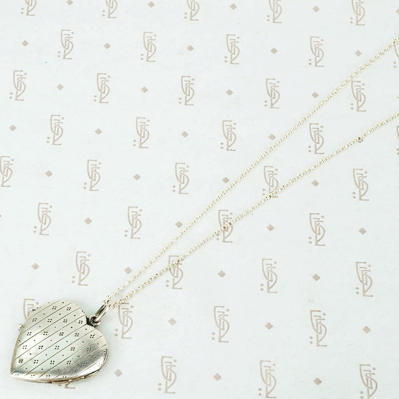 silver hearl locket with an interesting petit point design