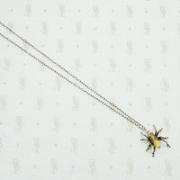 sterling silver with gold details this spider pendant is set with an opal body and garnet eyes