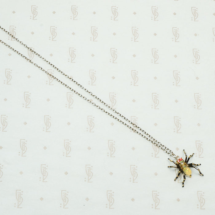 sterling silver with gold details this spider pendant is set with an opal body and garnet eyes