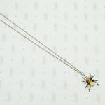 sterling silver with gold details this spider pendant is set with an opal body and garnet eyes