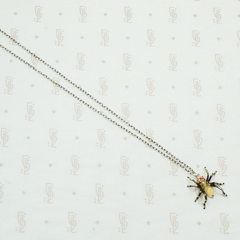 sterling silver with gold details this spider pendant is set with an opal body and garnet eyes