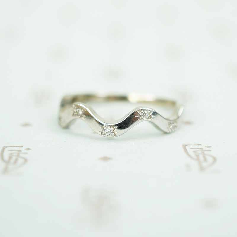 14k recycled white gold star set 5 diamond band with a curving wave design