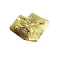 back view of antique sash pin in jewelers brass with a dragon and a snake and yellow glass gem