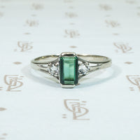 emerald cut gren tourmaline flanked by round white sapphires in 10k white gold ring